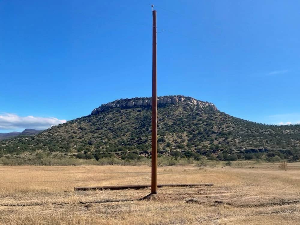 Steel Distribution Pole in field in front of a hill